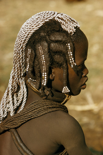 unrar:    A Mwila teen wears her hair in heavy coils adorned with beads, Angola,