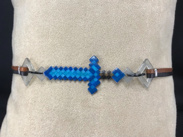 photo of a choker with a horizontal minecraft diamond sword shaped charm at the center held by two thin strips of leather.