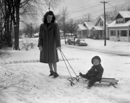Mrs. William O. Snyder, of 234 Dickinson in Grand Rapids, pulls her infant daughter on a sled - 1946