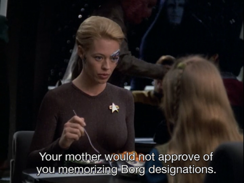 Seven of Nine and Naomi Wildman are sitting at a table in the Mess Hall of Voyager, eating. Seven is saying to Naomi, “Your mother would not approve of you memorizing Borg designations.”