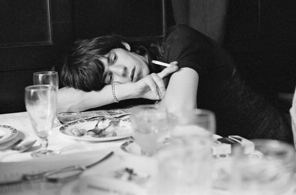 Terry O'Neill, Keith Richards slumps on a restaurant table staring into the middle distance holding a lit cigarette, London, 1964