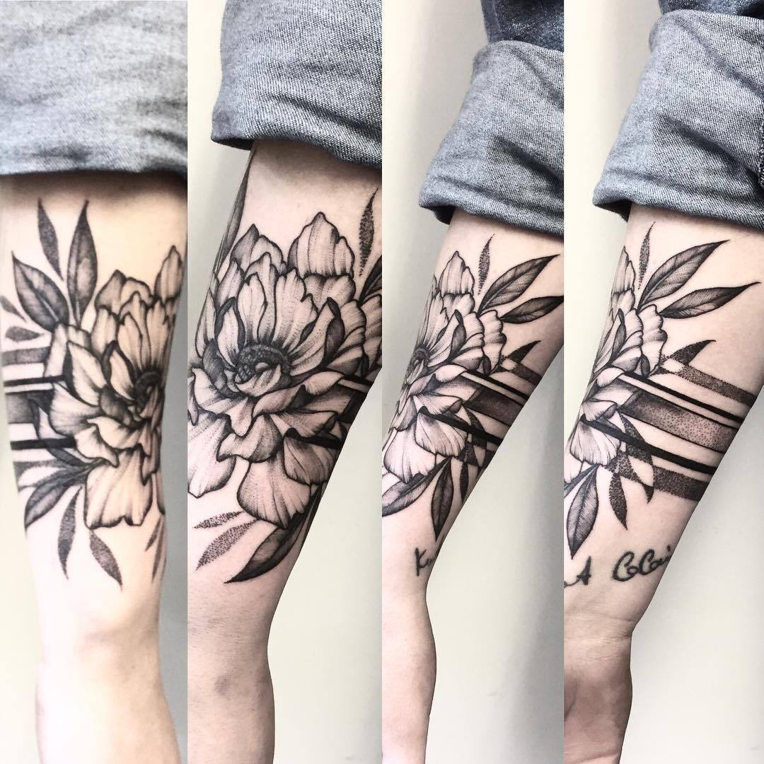 The Woman's Forearm Tattoo Features A Beautiful Design Of Flowers And White  Leaves. The Tattoo Is Done In A Traditional Style With Light Green And Dark  Gray Colors, Graphic Black Outlines, And