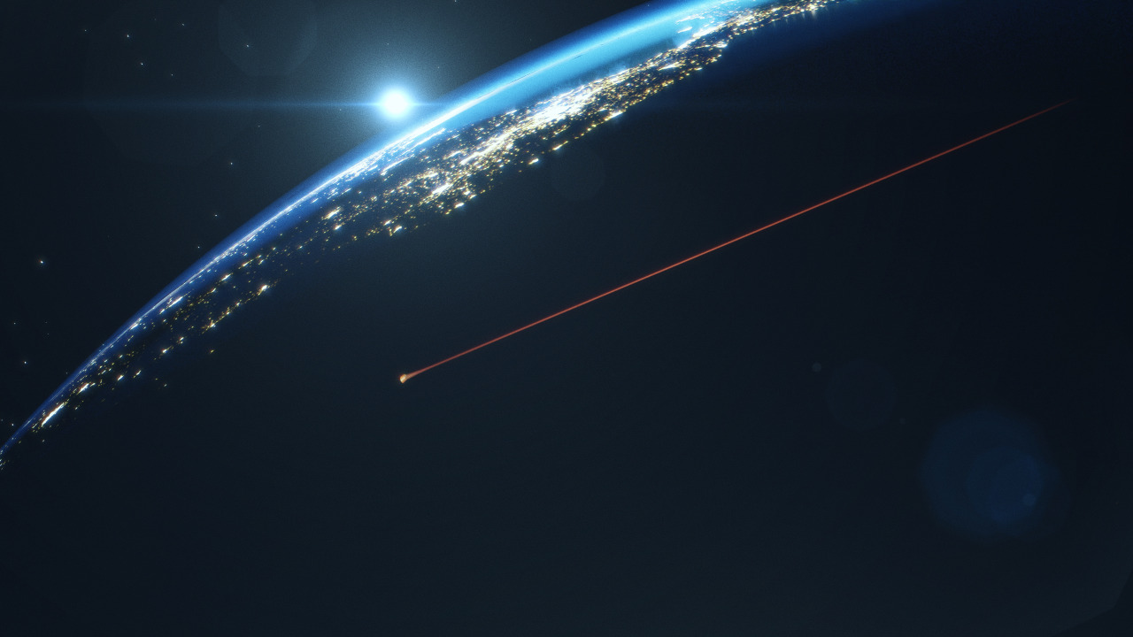 An artist’s rendition of the Orion spacecraft reentering Earth’s atmosphere. Orion is an orange streak coming from the top right to the left center of the photo, and Earth is seen at night with city lights as dots and a thin strip of atmosphere beneath the Sun.  Credit: NASA/Liam Yanulis