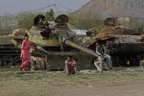 Afghan boys play on the remains of an old Soviet tank on the outskirts of Kandahar, south of Kabul, 