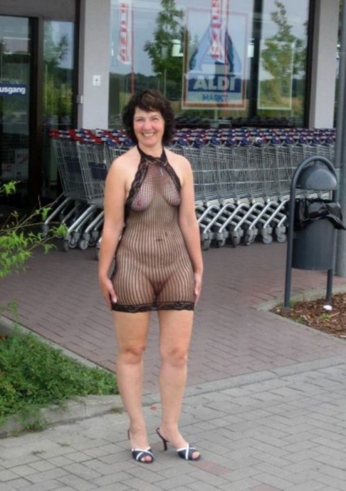 carelessinpublic:Almost nude mature lady outside a shop in her transparent fishnet dress and showing