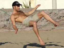 musclsvg: A hairy, bare chested, beach stud reclines balancing on a slack line by using the strength of the stacked abs on his muscular physique. Original photo by MuscleSavage. 