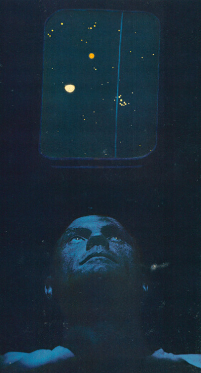 Astronaut John Glenn peers through a simulated capsule window, he observes star groupings at the Morehead Planetarium in North Carolina. Sighting on the vertical blue line which represents his flightpath, he learns to recognise the stars he will need