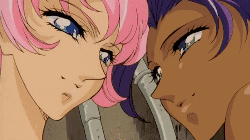 A GIF from the movie Adolescence of Utena, showing Utena and Anthy kissing. Utena is a light-skinned Japanese teenage girl with short pink hair and Anthy is a dark-skinned desi girl with long purple hair.