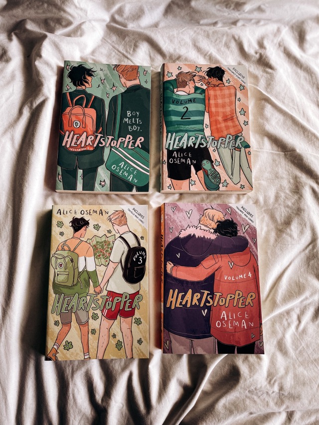 a flatlay photo of all four volumes of Heartstopper sit in the centre of a white sheet