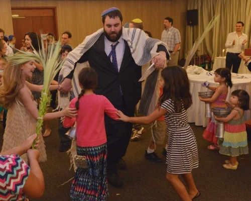 Rabbi Nathan Alfred dances with young Jewish children during Simchat Torah at the United Hebrew Cong