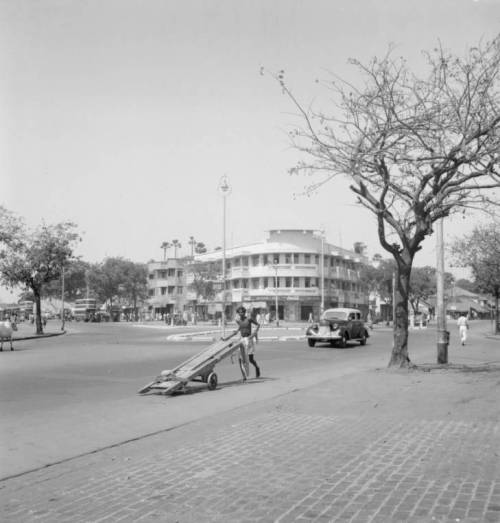 Clarence W. SorensenIndia, man pushing wheelbarrow on road in Mumbai (1952)The shop with a Coca Cola