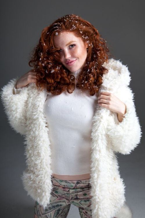 Graciela Rae in white ribbed wool sweater, leggings with dollar bill print and white fur coat