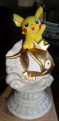pokescans:  Pikachu on golden Magikarp statue