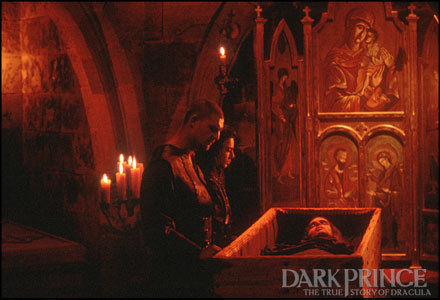 Menino vampiro de halloween acena sua capa preta e vermelha com as mãos  rodeadas sobre o fundo vermelho do estúdio. maquiagem de vampiro de  criança.