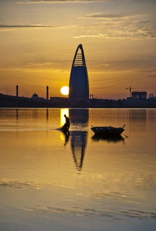 Khartoum, SudanA Sudanese fisherman reels in his net at dusk as Khartoum’s modern glass towers stand