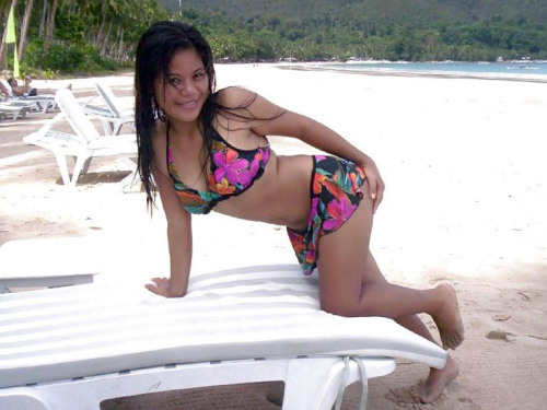 Filipina women in flower bikini on a tropical beach. Observe, how little other people are there. It&