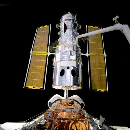 Attached to the “robot arm” the Hubble Space Telescope is unberthed and lifted up into t