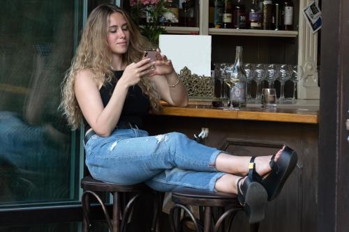 Friday night at the bar. College girl is occupied with her smartphone