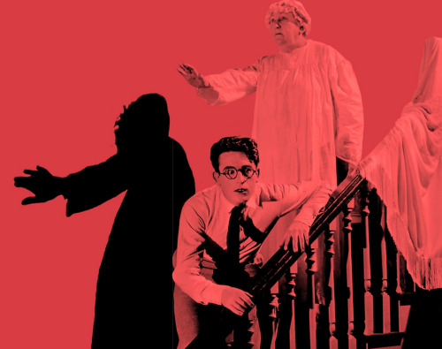 A still from a Harold Lloyd silent film with Lloyd leaning against a bannister with a ghostly person in white robes above him extending an arm.