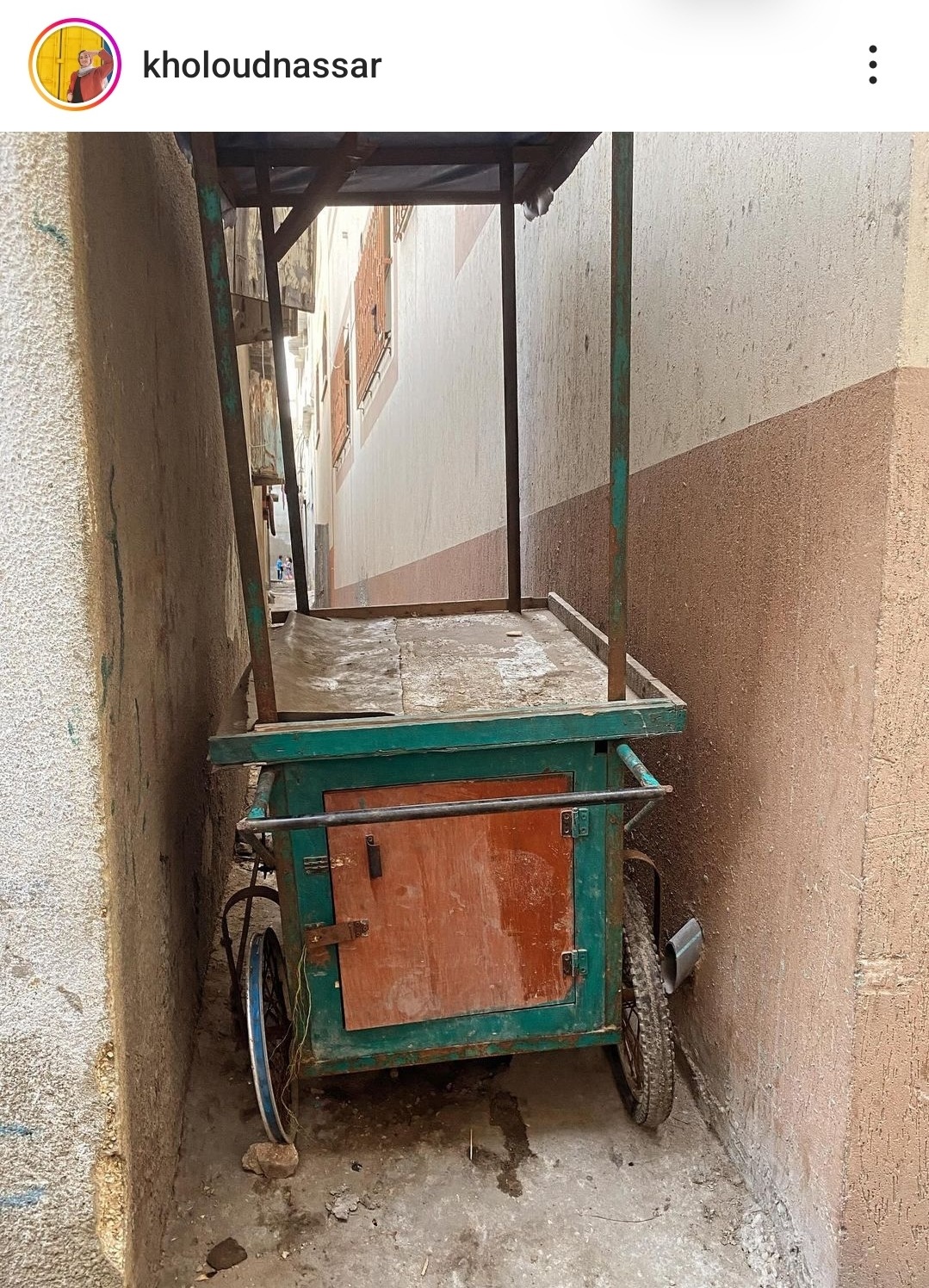 A photo of a broken vendor's cart sitting in an alley way.