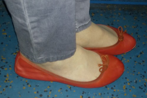 Red leather ballet flats worn with grey skinny jeans