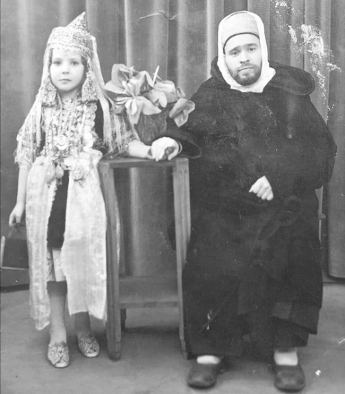 Algeria. Studio portrait of a father and his daughter in traditional attire, Tlemcen. While the fath