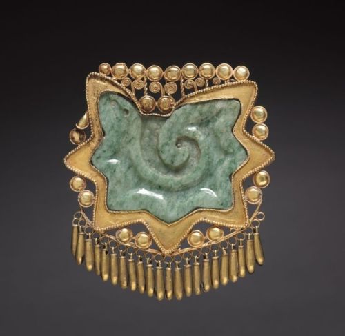 This extraordinary pendant consists of a conch shell section carved in jade, enclosed in a delicate 