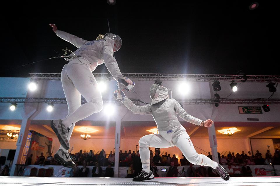 modernfencing:  [ID: a sabre fencer leaping at her opponent.] Monica Aksamit (left)