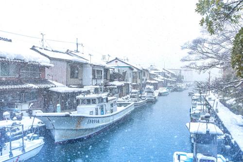 深々と降る雪。舞鶴市 吉原入江、伊佐津川の橋の上より風情ある漁港の情緒溢れる街並み。