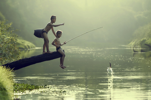 Asian boy fishing in a river. by Mingmuang