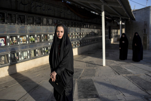 farsizaban:A woman in a cemetery in the centre of Qom, Iran. Behind her are memorial photographs of 