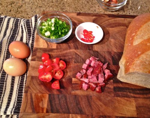 Breakfast bite: eggs on bread with smoked sausage, scallion, cherry tomato, and a hot red Thai chili