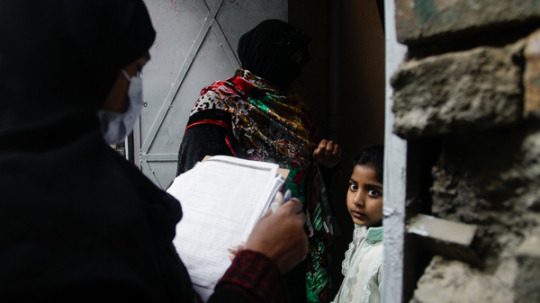 Polio vaccinator Zeenat Parveen, holding the clipboard, and a volunteer go door-to-door to reach children in Rawalpindi, a city near the Pakistani capital of Islamabad.