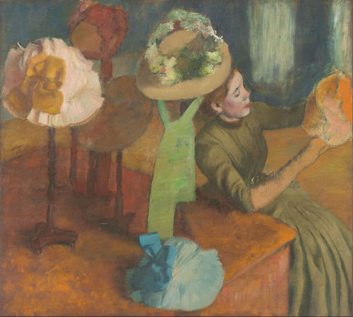 blondebrainpower:The Millinery Shop (1879/86) is a painting by French artist Edgar Degas. It depicts a woman sitting at a display table in a millinery shop, appearing to closely examine or work on a lady’s hat, which she holds in her hands. The view