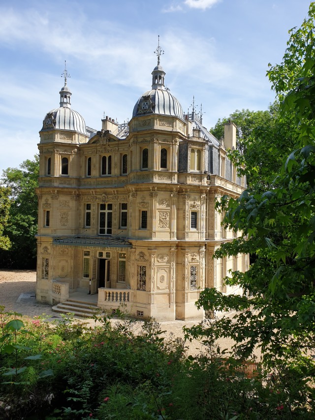 a picture of a small sandstone castle with extremely elaborate stonecarving everywhere. the roof has fringe.