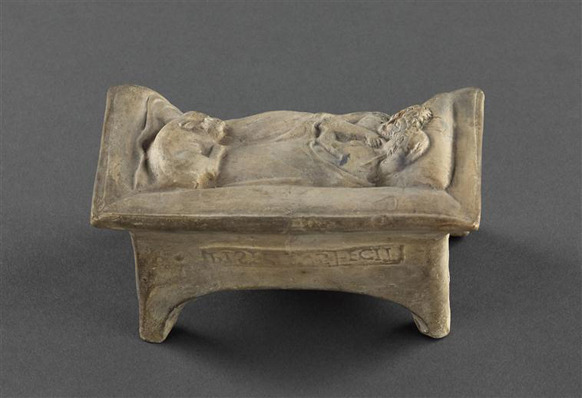 The back of a terracotta model of two people embracing in bed, where words in Latin reading "Pistillus fecit" have been stamped. The reverse view of the same object in the previous two photos.