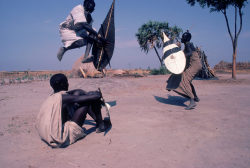 southsud:   Nuer warriors with shields and clubs leap during mock combat at a cattle camp on the edge of the Sudd swamp in southern Sudan.    Photograph by: Robert Caputo / Aurora Photos      