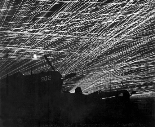 Ryukyu Islands Okinawa, Japan Yontan airfield AA against Japanese night raiders during WWII; F4Us Hell’s Belles squadron in fore.photo by T. Chorlest, 1945