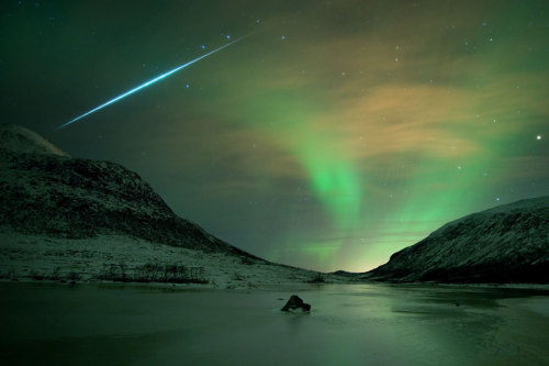 The sudden flash of a fireball meteor from the 2009 Geminid meteor shower streaks across an Aurora B
