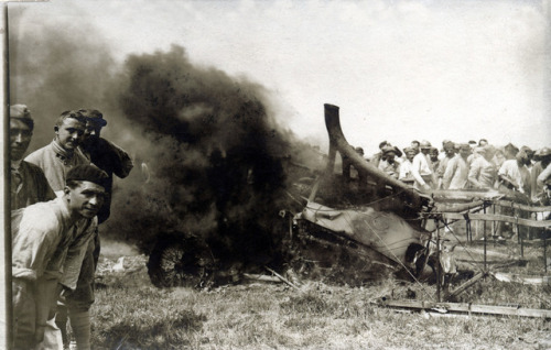 A smouldering German aircraft shot down near Reims (May 20th, 1917), with French soldiers standing a