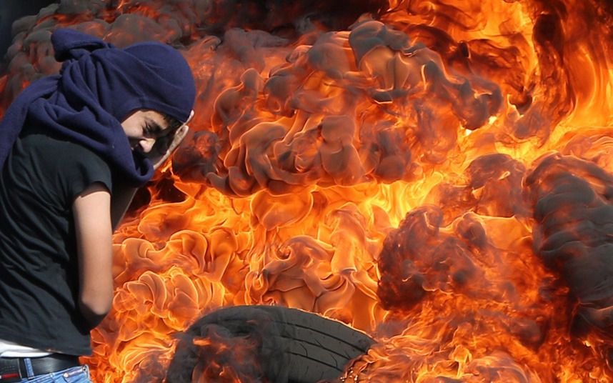 letswakeupworld:  A Palestinian protester protects his face as he stands in front