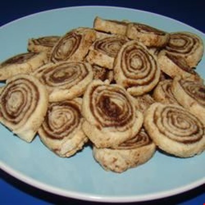 Pie crust is rolled out, sprinkled with cinnamon and sugar, and rolled into a log to be sliced into 