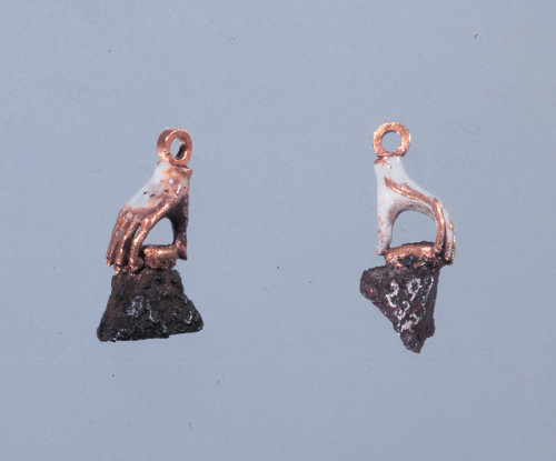 roses–and–rue:These enamel earrings in the shape of hands hold pieces of shrapnel remove