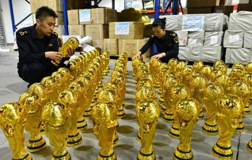 Chinese customs officers checks a seized fake World Cup trophy at a wa