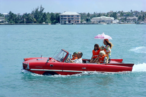 Thunderball producer Kevin McClory and family riding in an Amphicar; photo by Slim Aarons; Bahamas, 