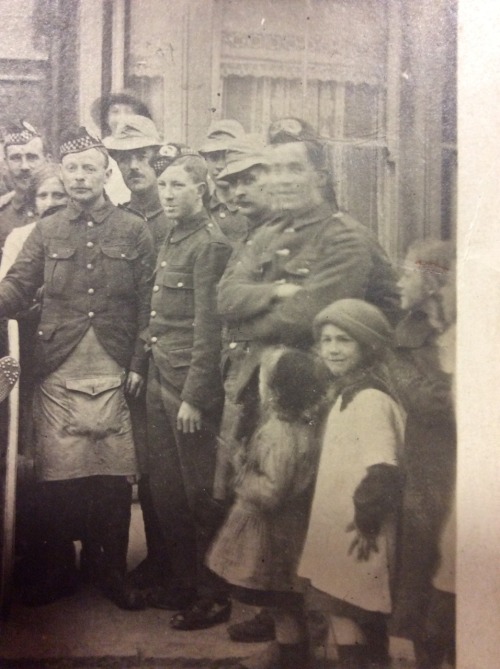 ….At the edge of a group shot a child in a woollen hat stares into the camera.  She looks tro