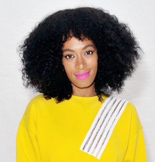 Solange Knowles with voluminous hair and a neon pink lip