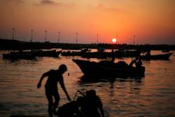 biladal-sham:  Palestinian boys prepare a fishing net during sunset at the seaport of Gaza City. Mohammed Salem