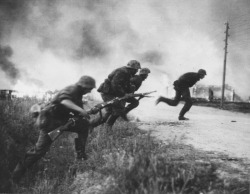 opacasilentianoctis:  Soldiers of the SS Division “Das Reich” run across the road on the background of the burning of the Soviet countryside. 