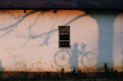 A shadow of a man holding a bicycle is cast on a wall near the Zambezi River, 1996. Photograph by Ch